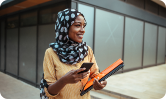 Smiling woman holding a smartphone and folders, representing bank account verification process outdoors.