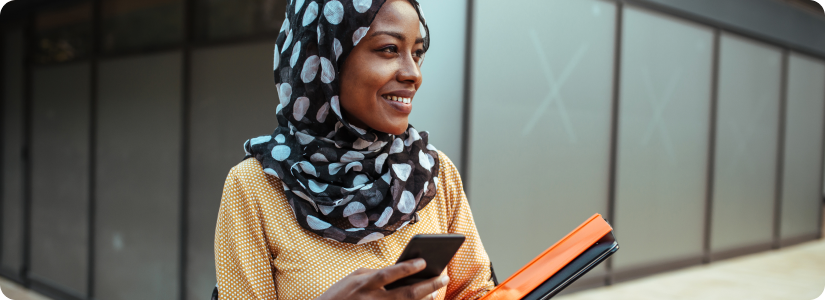 Smiling woman holding a smartphone and folders, representing bank account verification process outdoors.